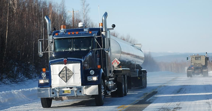 Truckers navigating a winter road, equipped with techniques to identify and manage slippery surfaces for safe driving.